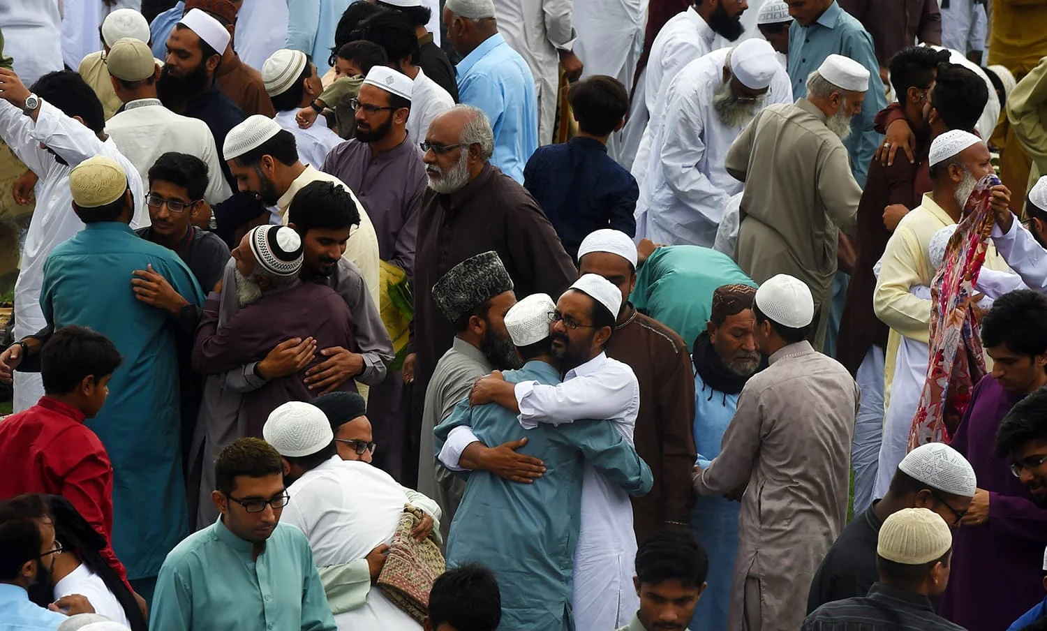 A large crowd of people celebrating Eid ul-Fitr, joyfully gathered together in a festive atmosphere.